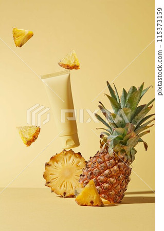 Tropical summer style photograph of frontal shot for pineapple extract cosmetics, a yellow tube without label displayed on a slice of pineapple, beside some pineapple pieces flying in the air Tropical summer style photograph of frontal shot for pineapple extract cosmetics, a yellow tube without label displayed on a slice of pineapple, beside some pineapple pieces flying in the air 115373159