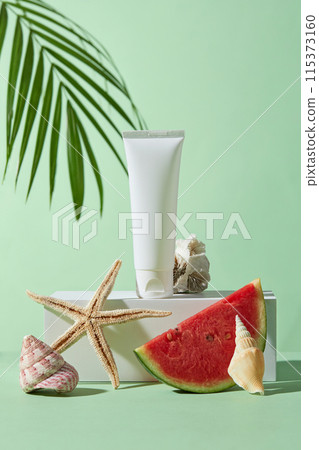 Photo of summer beach concept from front view with watermelon, coconut leaf, shell and coral decoration. Blank label cosmetic tube in white color displayed on a large podium in center, copy space Photo of summer beach concept from front view with watermelon, coconut leaf, shell and coral decoration. Blank label cosmetic tube in white color displayed on a large podium in center, copy space 115373160