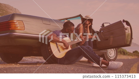 African american man playing guitar for his wife near the car on the street 115373413