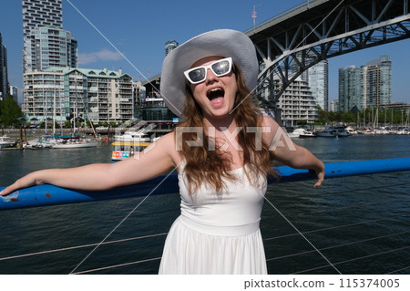 Greenville Island girl on the waterfront A woman tourist in a white hat and dress stands near the bridge 115374005
