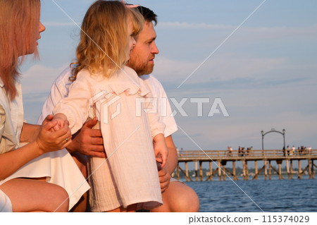 Young family Mother father and daughter on the beach looking at the sea 115374029