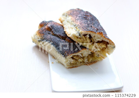 strudel with apples sprinkled with poppy seeds on a white flat plate and light background no other ingredients clean space for your text delicious food cooking homemade baking products healthy food 115374229