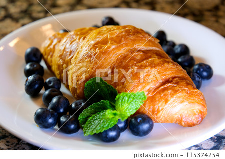Extreme close up powdered sugar is poured onto croissants with blueberry. strainer with flour or sugar, which is sprinkled with baked goods before serving. Breakfast or dessert cooking concept 115374254