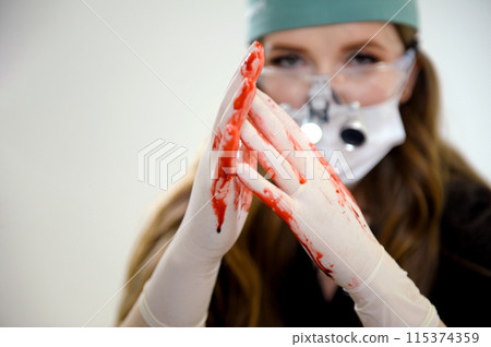 a female doctor rubs blood on her hands shows a heart saving the dying operation was successful binoculars on the nose latex gloves white background a female doctor rubs blood on her hands shows a heart saving the dying operation was successful binoculars on the nose latex gloves white background 115374359