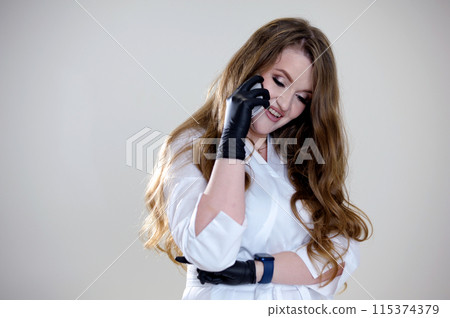 I am here. Pretty woman sitting on phone on white background beautiful woman with makeup talking on the phone black latex gloves white clothes I am here. Pretty woman sitting on phone on white background beautiful woman with makeup talking on the phone black latex gloves white clothes 115374379