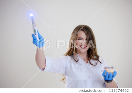 Photopolymer lamp a woman doctor like a Fairy waves a polymer lamp like a magic wand in a white suit on a white background conjures fascinates treats for children fairy tale 115374462
