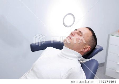View of modern dental surgery Successful dentist appointment Successful dentist appointment dentist treating teeth of male patient in modern dental office 115374464