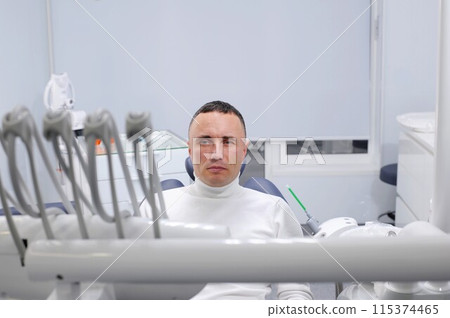 View of modern dental surgery Successful dentist appointment Successful dentist appointment dentist treating teeth of male patient in modern dental office 115374465