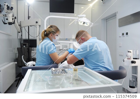 Medical treatment at the dentist office Side view patient and preparing him for the treatment. Serious man in dentist chair looking at the doctor and asking for something Dentist and patient 115374509