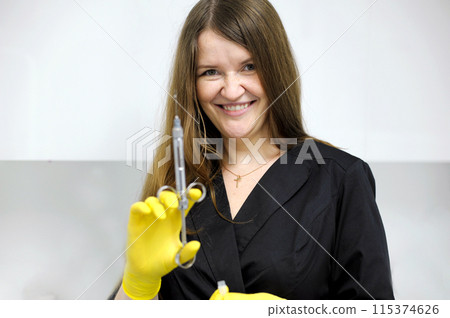 Black clothes long flowing hair white cabinet office dentistry Young girl woman with syringe in hand anaesthesia yellow gloves doctor nurse Doctor, girl, syringe injection Black clothes long flowing hair white cabinet office dentistry Young girl woman with syringe in hand anaesthesia yellow gloves doctor nurse Doctor, girl, syringe injection 115374626