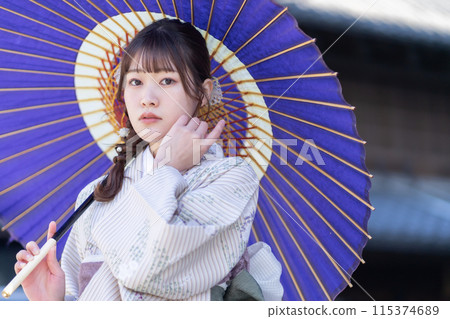 一位穿著和服的年輕女子拿著日本傘擺姿勢 一位穿著和服的年輕女子拿著日本傘擺姿勢 115374689