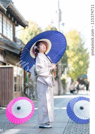一位穿著和服的年輕女子拿著日本傘擺姿勢 一位穿著和服的年輕女子拿著日本傘擺姿勢 115374711