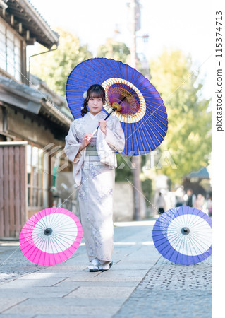 A young woman in a kimono posing with a Japanese umbrella A young woman in a kimono posing with a Japanese umbrella 115374713