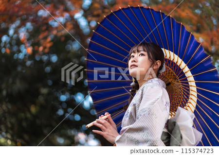 A young woman in a kimono walking through an ancient city with autumn leaves A young woman in a kimono walking through an ancient city with autumn leaves 115374723