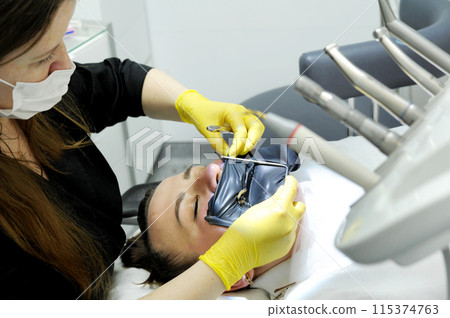 cofferdam clamp for cofferdam The process of dental prosthetics using a microscope, female doctor in yellow gloves, patient dentist with patient, using dental curing light cofferdam clamp for cofferdam The process of dental prosthetics using a microscope, female doctor in yellow gloves, patient dentist with patient, using dental curing light 115374763