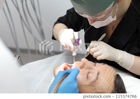 woman doctor dentist removes man patient tooth heavy easy extraction hard tooth extraction, tooth extraction tools Gracie curette, piezo scaler, piezo scaler attachment, piezo scaler wrench, luxator, woman doctor dentist removes man patient tooth heavy easy extraction hard tooth extraction, tooth extraction tools Gracie curette, piezo scaler, piezo scaler attachment, piezo scaler wrench, luxator, 115374766