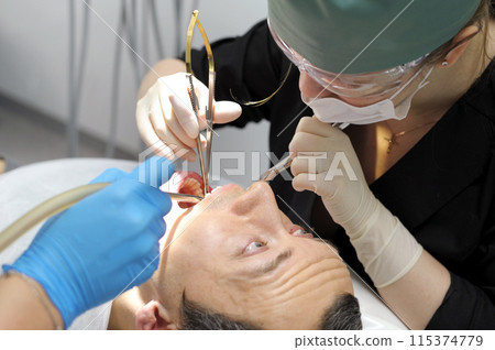 pull a tooth out adult man praying with his eyes looks at the doctor who tears his tooth dentistry hurts the request of a man woman 115374779