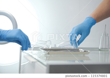 doctor nurse at same time put plastic transparent glasses on a glass table with instruments for operations stomatology hospital hospital blue gloves sterile protective glasses close-up modern clinic 115374801