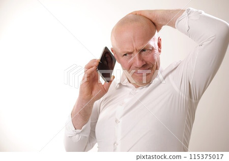 Senior man feeling upset having phone conversation depressed by hearing bad news adult man in white shirt grabbed his head and is upset, he listens to the news from the phone, he is talking to someone Senior man feeling upset having phone conversation depressed by hearing bad news adult man in white shirt grabbed his head and is upset, he listens to the news from the phone, he is talking to someone 115375017