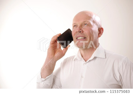 male pensioner looks up he holds phone pleasantly expects winning hope yes opportunities for salary increase white studio shirt there is space for text portrait of an adult male confident bald no hair male pensioner looks up he holds phone pleasantly expects winning hope yes opportunities for salary increase white studio shirt there is space for text portrait of an adult male confident bald no hair 115375083