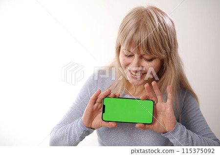 thumbs up show class pretty sweet woman in white hoodie looks at the phone, she is glad that she sees there and shows the phone with green screen to camera. Happy lady shares information with us 115375092