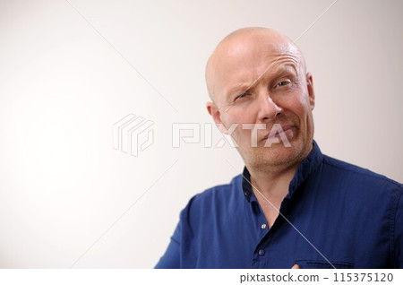 Emotions of an adult handsome bald man A man on a white background in a blue shirt There was some kind of surprise man looks and can not believe in the situation negative emotion 115375120