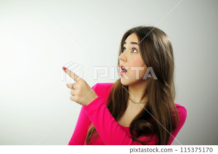 Place for text advertising sales Insanely beautiful young woman girl with long brown hair in a pink sweater on a white background different emotions Many positive emotions joy happiness fun success 115375170