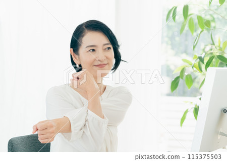 A woman stretching in front of a computer 115375503