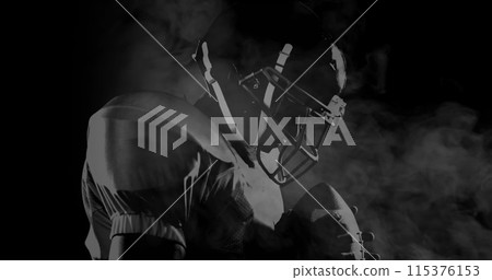 Image of male american football player over smoke on black background 115376153