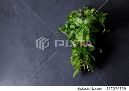 Fresh organic mint on rustic black stone table background. Selective focus. Fresh organic mint on rustic black stone table background. Selective focus. 115376169