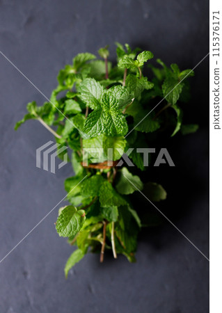 Fresh organic mint on rustic black stone table background. Selective focus. Fresh organic mint on rustic black stone table background. Selective focus. 115376171