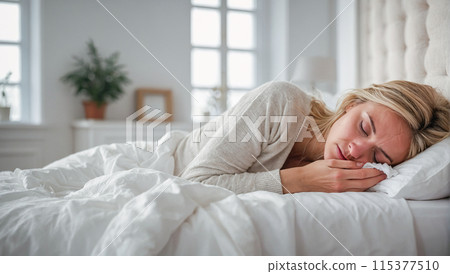 Portrait of a sick or tired woman lying in a white bed at home. 115377510