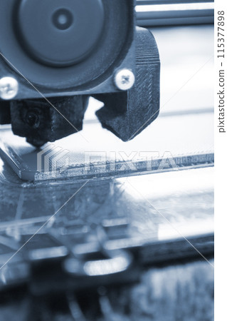 3D printer printing a model. Equipment of a 3D printer during the process of printing a model from molten plastic 115377898