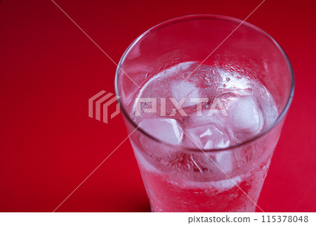 Ice in a glass on a red background Ice in a glass on a red background 115378048