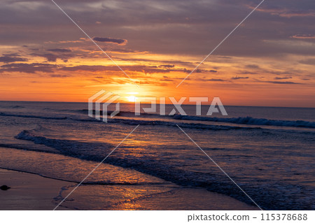 Enjoy a tranquil sunset on the shore with gentle waves creating a serene and peaceful atmosphere 115378688