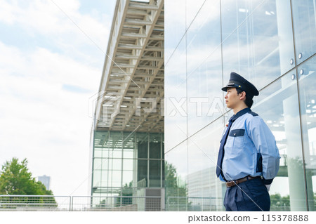 A security guard looking up at the sky in front of a building 115378888