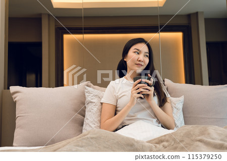 Asian woman holding a cup of coffee in the morning after waking up. 115379250
