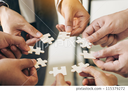 The concept of teamwork and partnership. Businessman's hands putting together puzzle pieces in the office and join together in a jigsaw puzzle team. Charity. Volunteers. Business unity as a team. The concept of teamwork and partnership. Businessman's hands putting together puzzle pieces in the office and join together in a jigsaw puzzle team. Charity. Volunteers. Business unity as a team. 115379272