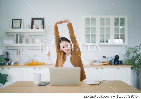 Young asian woman feeling pain in neck and shoulder after working on computer laptop for a long time 115379976
