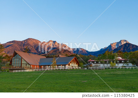 View of the Yatsugatake mountain range bathed in the morning sun from the Kiyosato Plateau in the early morning, spring 115380425
