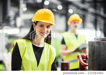 Warehouse employees in warehouse. Two workers in reflective clothing in modern industrial factory, heavy industry, manufactrury. Warehouse employees in warehouse. Two workers in reflective clothing in modern industrial factory, heavy industry, manufactrury. 115381491