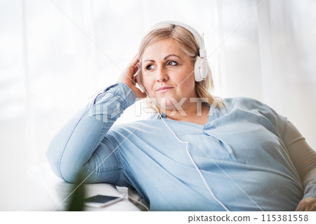 Portrait of beautiful young overweight woman at home, listening music via headphones, mediating, enjoying peaceful weekend day. Portrait of beautiful young overweight woman at home, listening music via headphones, mediating, enjoying peaceful weekend day. 115381558