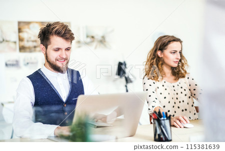 Two colleagues working on a new project together in a startup company office. Working in co-working space. Two colleagues working on a new project together in a startup company office. Working in co-working space. 115381639