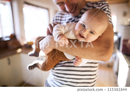 Handsome dad holding small baby, carrying him around house. Unconditional paternal love, father's Day concept. 115381844