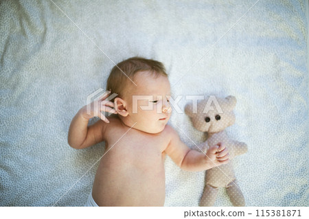 Portrait of cute little baby lying on bed, wearing diaper. Portrait of cute little baby lying on bed, wearing diaper. 115381871