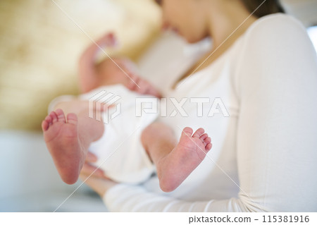 Mom holding newborn baby, looking at infant lovingly. Unconditional paternal love, Mother's Day concept. Mom holding newborn baby, looking at infant lovingly. Unconditional paternal love, Mother's Day concept. 115381916