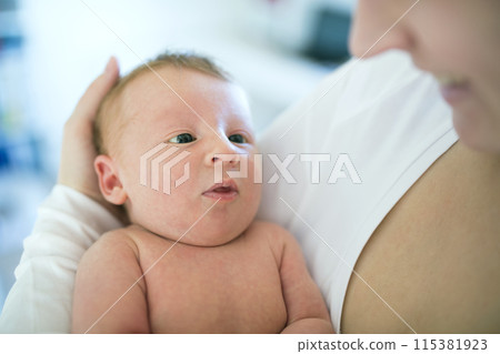 Mom holding newborn baby, looking at infant lovingly. Unconditional paternal love, Mother's Day concept. Mom holding newborn baby, looking at infant lovingly. Unconditional paternal love, Mother's Day concept. 115381923