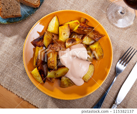 Spanish snack Patatas bravas, baked chopped potatoes with spicy aioli 115382137