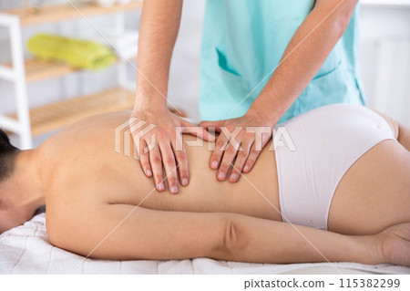 Masseur doing back massage to adult woman 115382299