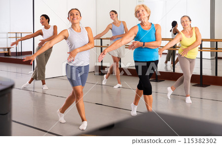 Group of active women practicing energetic dance in a studio 115382302